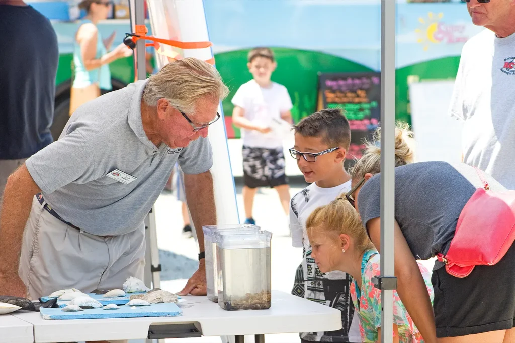 An educator shows children marine specimens and a tank of live sea creatures during Barnegat Bay Day at LBIF.