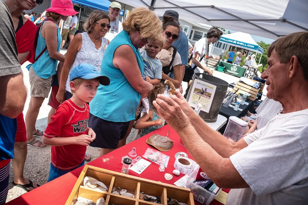 A boy listens attentively as an instructor shows a shell specimen at a marine life education booth during Barnegat Bay Day.