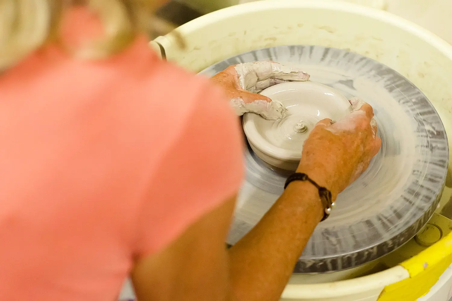 Artist shaping clay on a pottery wheel during a ceramics session at LBIF.