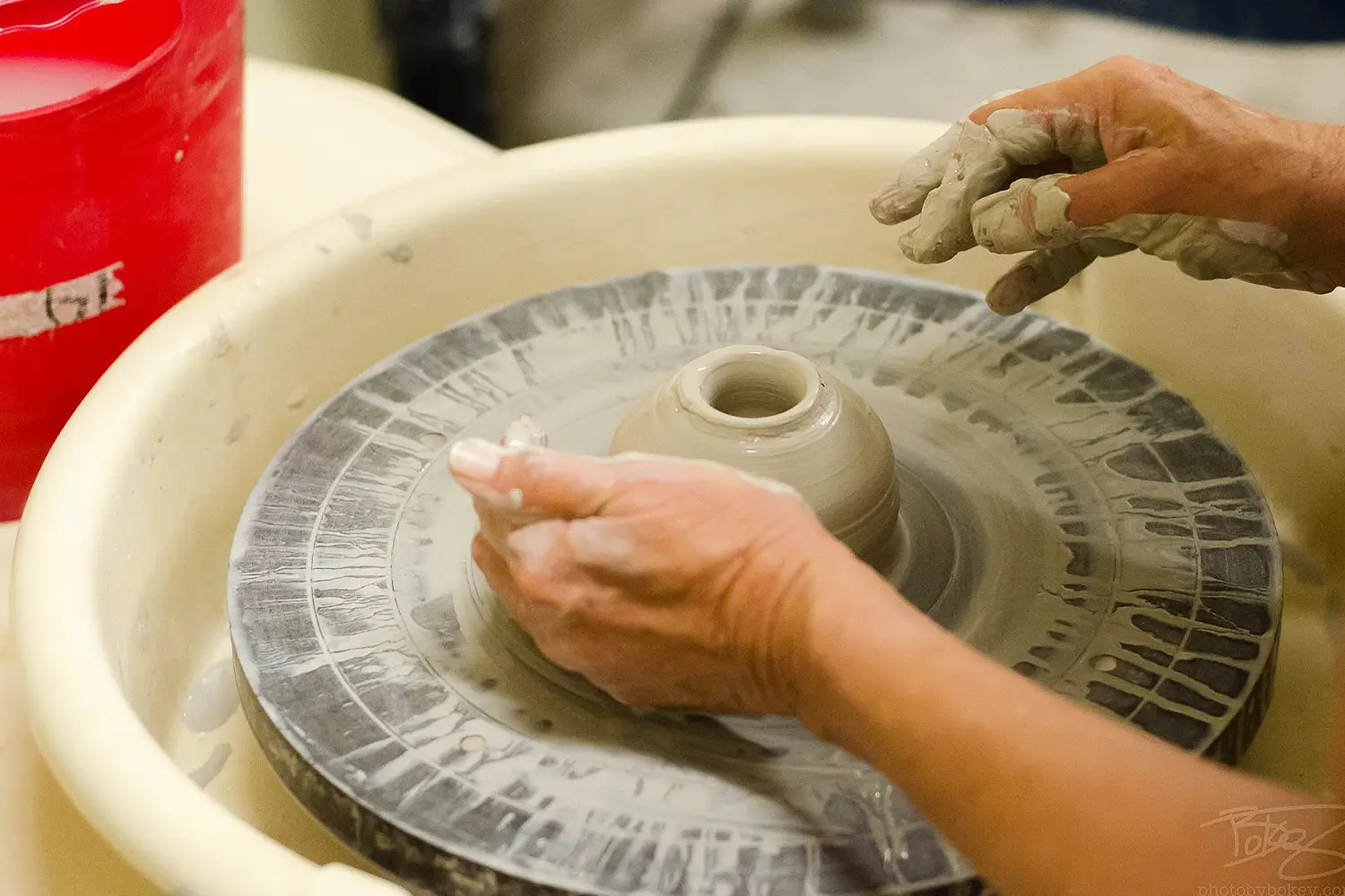 Hands shaping a small clay bowl on a pottery wheel in the LBIF ceramics studio.