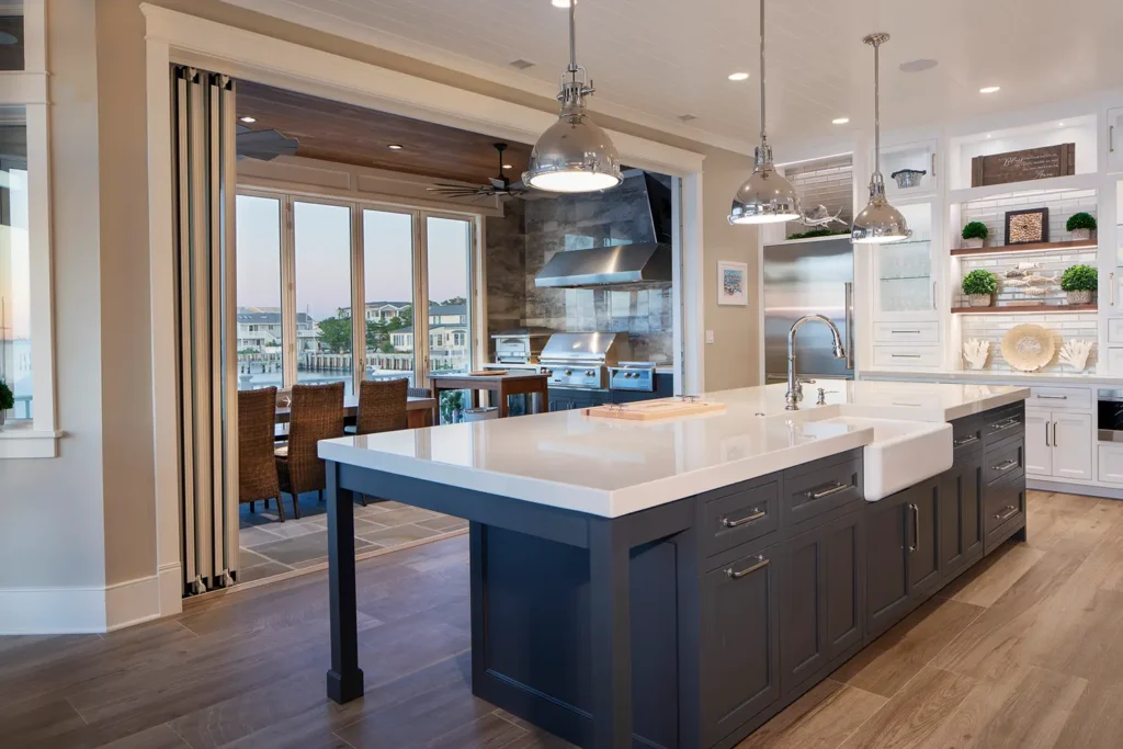 Modern coastal kitchen with large island and open view to outdoor dining area overlooking the bay, featured in the 2025 LBIF Annual Seashore House Tour.