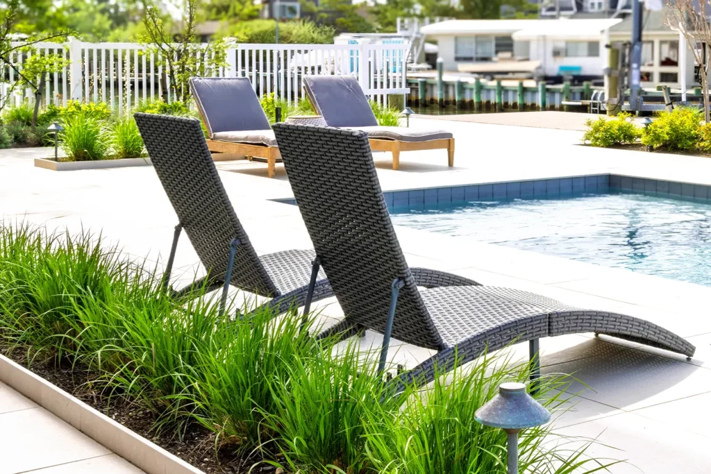 Poolside lounge chairs beside a modern backyard pool overlooking the bay, featured in the 2025 LBIF Annual Seashore House Tour.