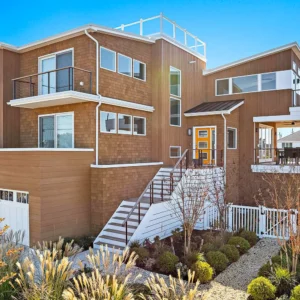 Modern coastal home with cedar siding, white trim, and multiple balconies, featured in the 2025 LBIF Annual Seashore House Tour.