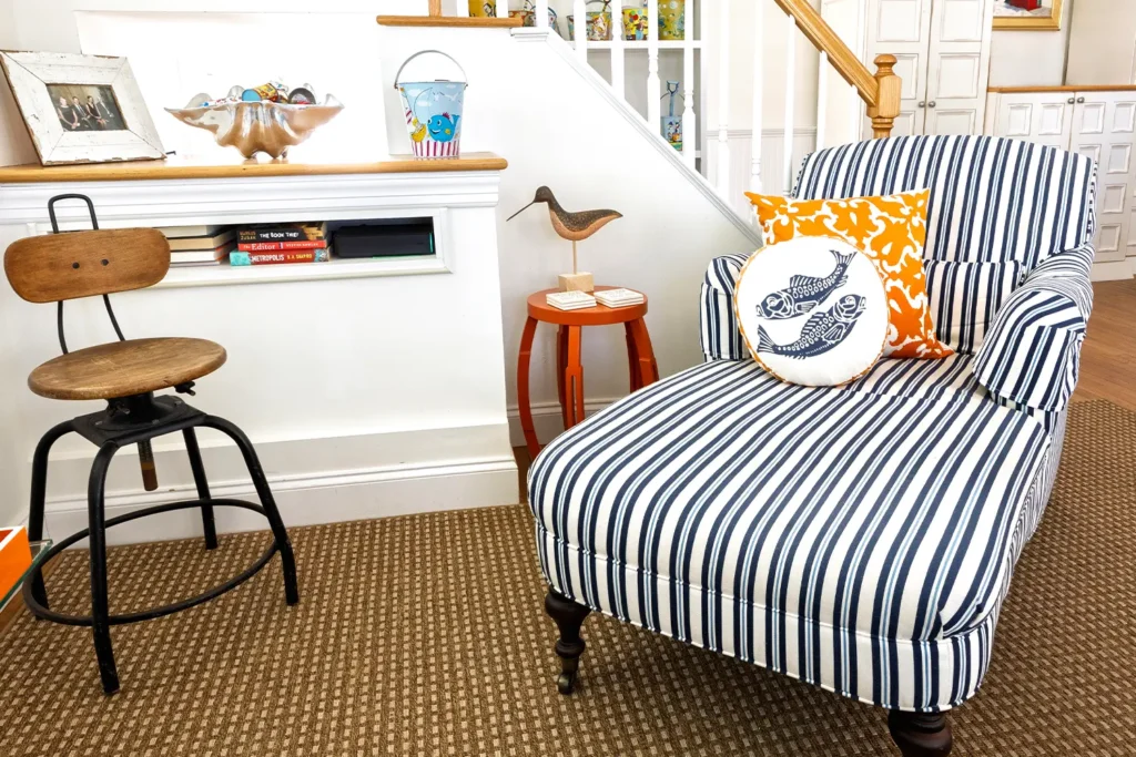 Coastal-inspired reading nook with striped armchair and nautical decor, featured in the 2025 LBIF Annual Seashore House Tour.