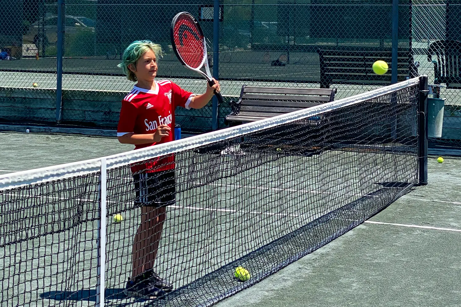 A camper practices hitting a tennis ball over the net during a sunny day at LBIF’s tennis courts.
