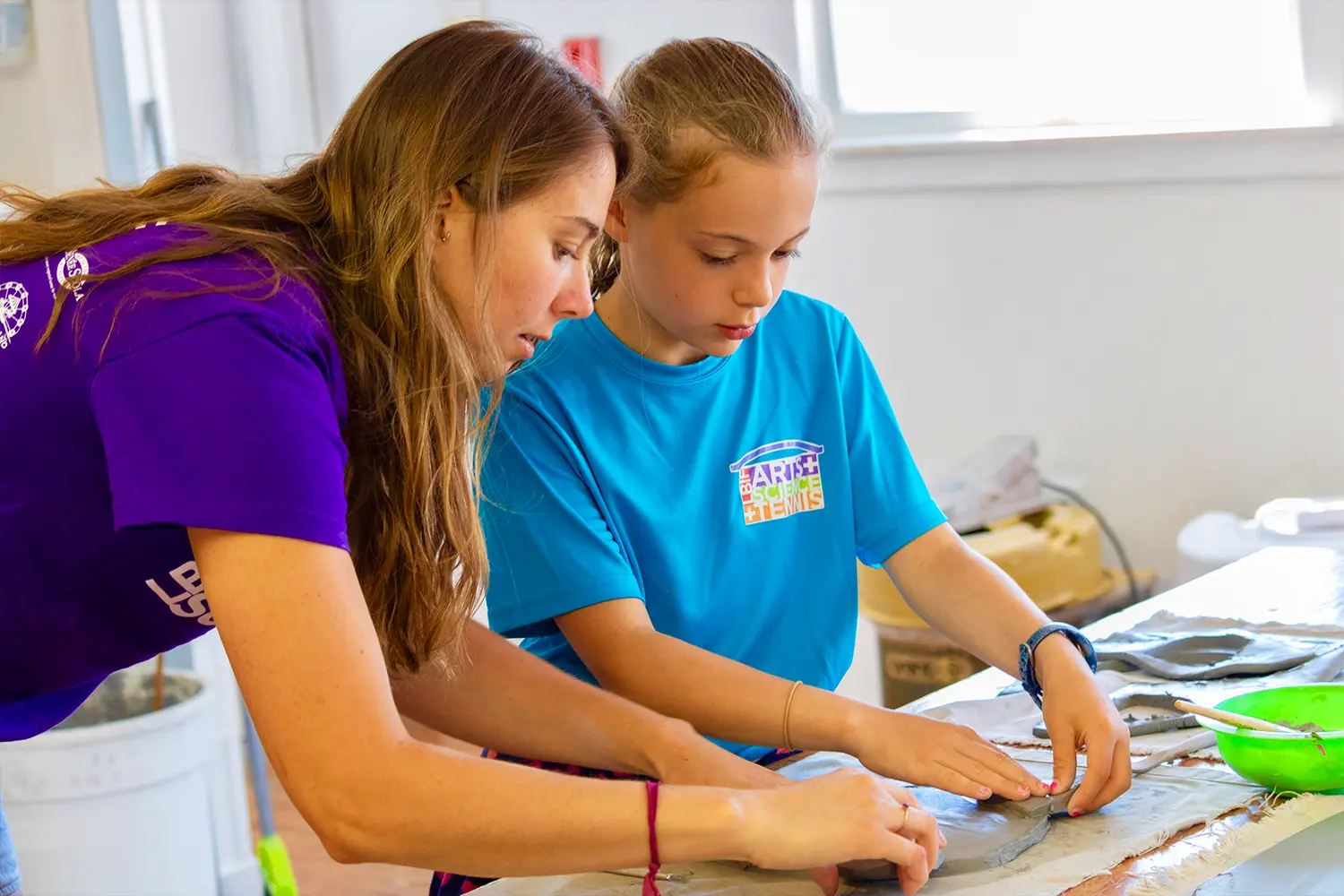 An instructor helps a camper shape clay during an LBIF ceramics class at Summer Camp.