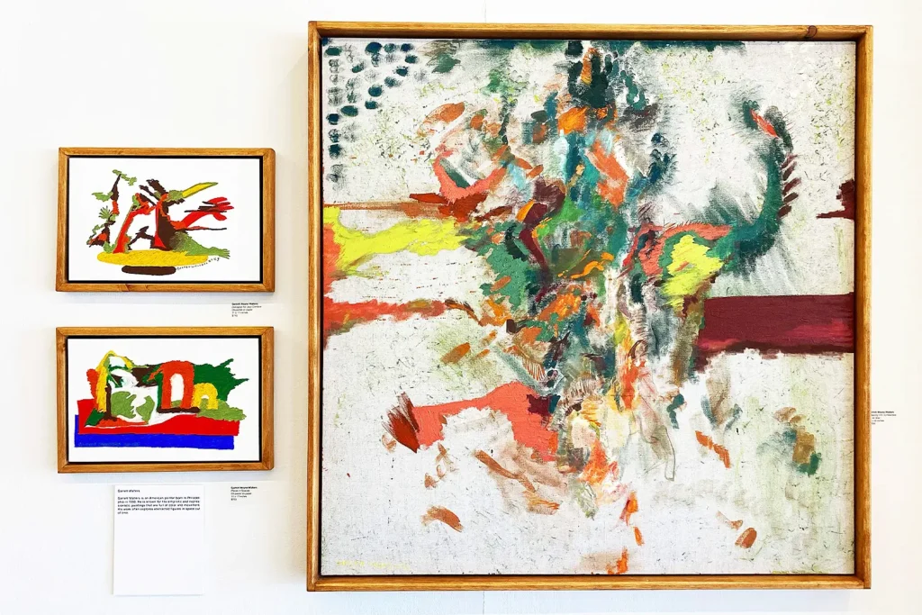 Three framed abstract paintings with vibrant colors and bold brushstrokes displayed on a white gallery wall.