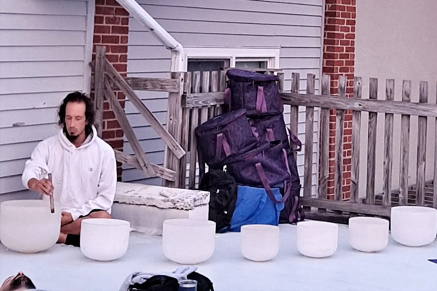 A yoga instructor plays crystal singing bowls during a sound healing session at LBIF, creating calming tones that fill the outdoor space.