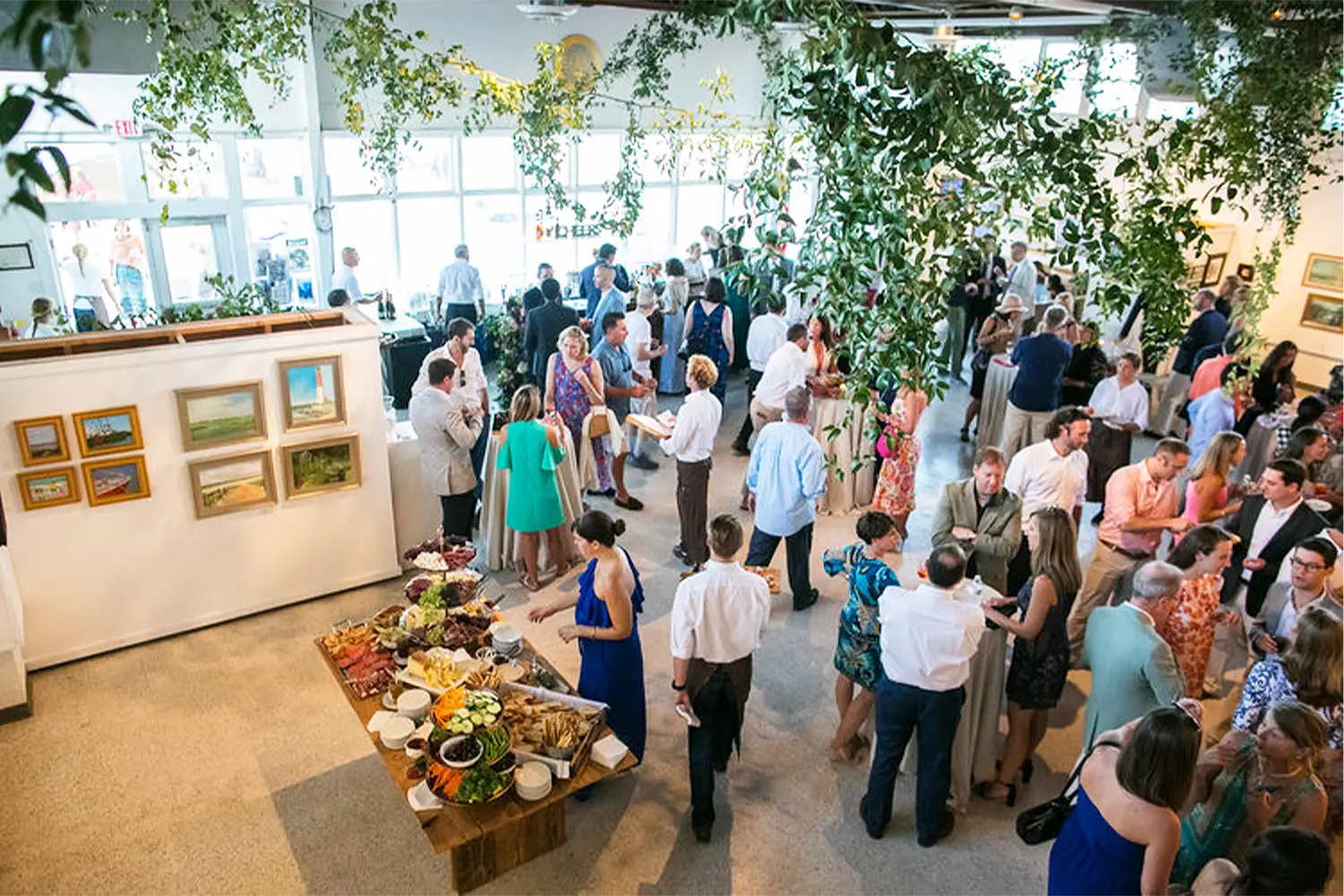 Guests mingle beneath hanging greenery in a bright gallery space during a private event at LBIF.