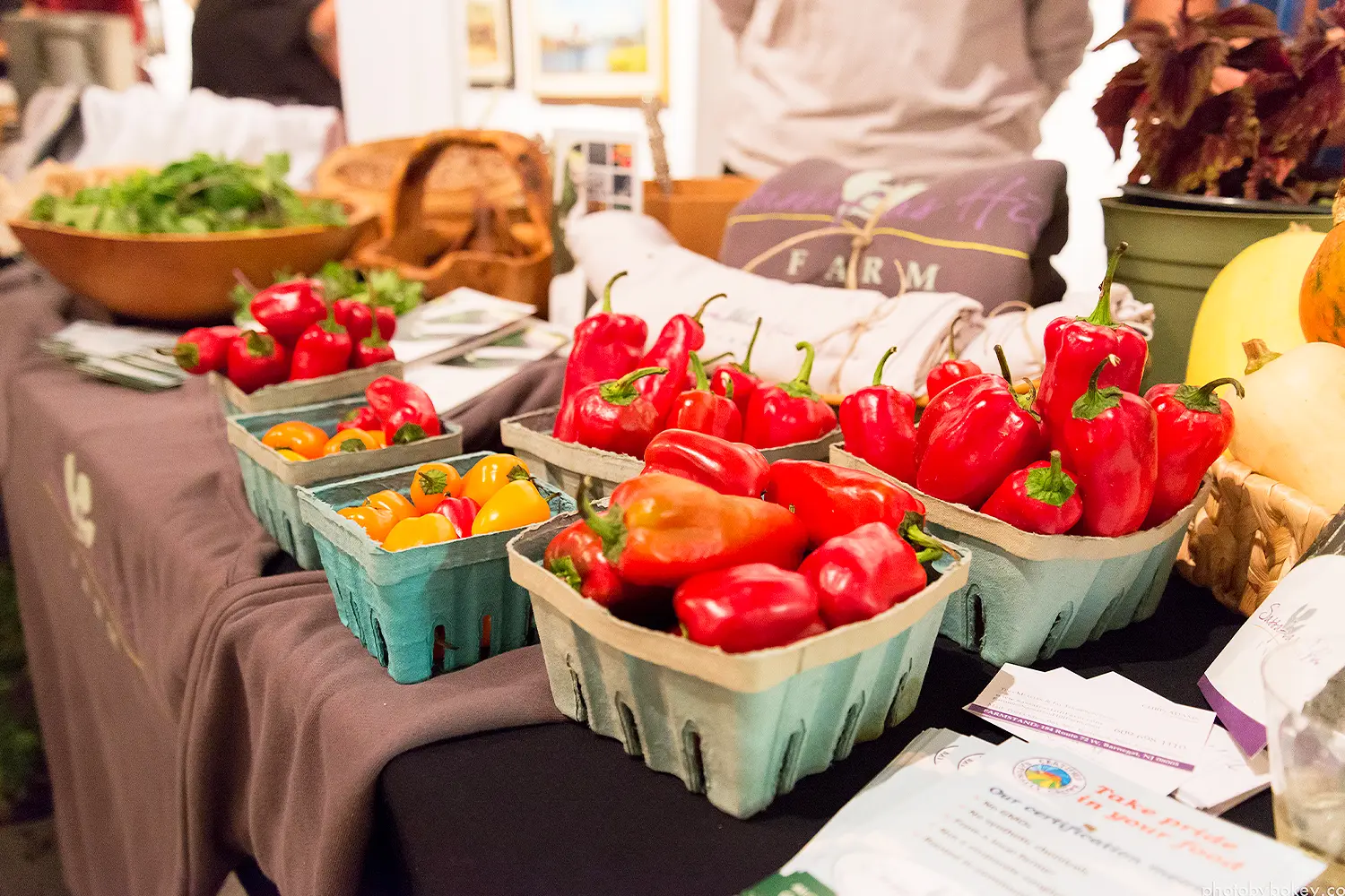 Baskets of red and yellow peppers displayed on a table at a local farm or market-style event.